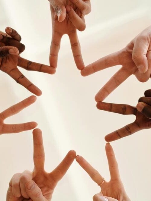 Gemeinschaft durch Vielfalt Sieben Hände bilden gemeinsam durch aneinandergelegte Zeige- und MIttelfinger einen Stern.